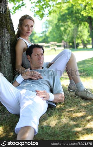 Portrait of sporty couple relaxing by tree