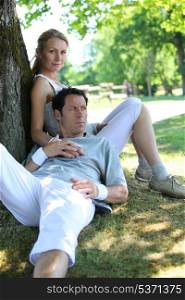 Portrait of sporty couple relaxing by tree