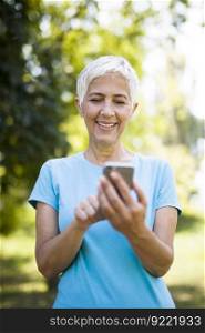 Portrait of sporty senior woman using mobile phone in the park