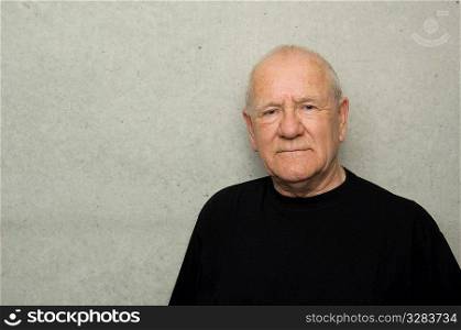 Portrait of stern looking older man, wearing black t-shirt.