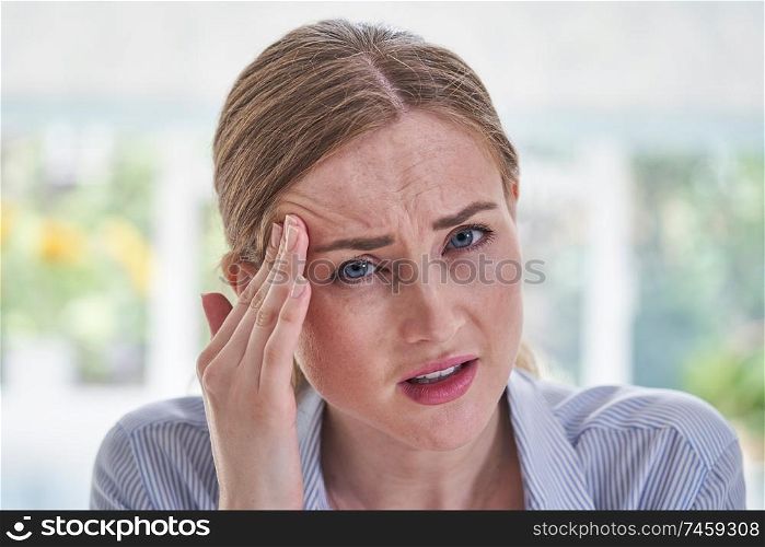 Portrait Of Stressed Businesswoman Suffering With Headache In Office