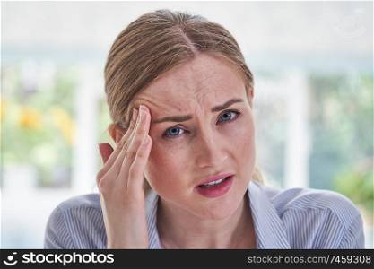 Portrait Of Stressed Businesswoman Suffering With Headache In Office