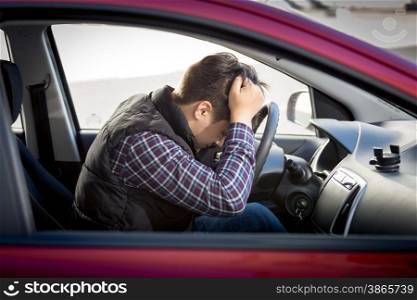 Portrait of stressed man sitting on car drivers seat