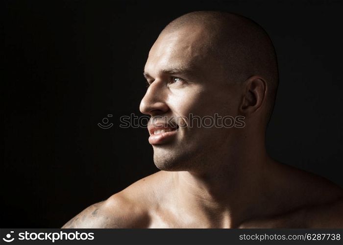 portrait of strong smiling man isolated on black background with copyspace