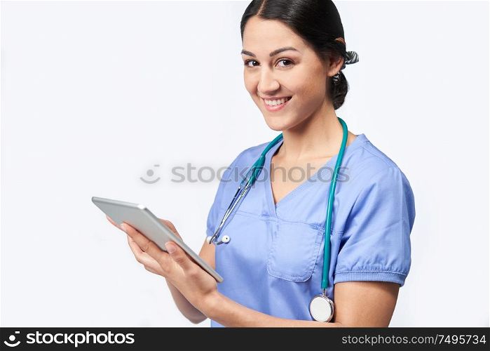 Portrait Of Studio Shot Of Female Nurse Wearing Scrubs Using Digital Tablet