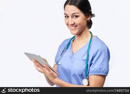 Portrait Of Studio Shot Of Female Nurse Wearing Scrubs Using Digital Tablet