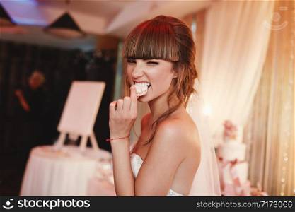 portrait of stylish cheerful bride eating french macaroon dessert. wedding and holiday concept.. portrait of stylish cheerful bride eating french macaroon dessert. wedding and holiday concept