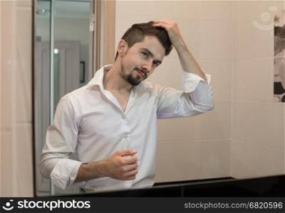 Portrait of stylish cheerful glad happy handsome cheerful young man combing his hair and laugh. Man take care about his hair. A man taking care of his hair. Sexy guy caring of his appearance.. Handsome man care about hair