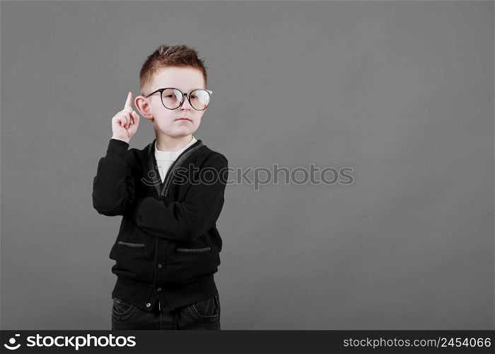 Portrait of stylish little boy with finger pointed up. Little child in glasses has idea. Kid isolated on blue blackboard. Success, bright idea, creative ideas and innovation technology concept. Portrait of stylish little boy with finger pointed up. Little child in glasses has idea. Kid isolated on blue blackboard. Success, bright idea, creative ideas and innovation technology concept.