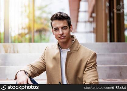Portrait of stylish young man with coat sitting on a stairs