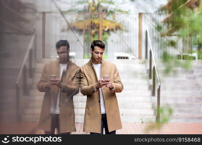 Portrait of stylish young man with coat standing outdoors and leaning on wall.