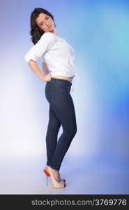 Portrait of stylish young plus size woman in fashion jeans high heels on blue background.