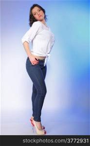 Portrait of stylish young plus size woman in fashion jeans high heels on blue background.