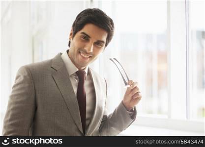 Portrait of successful businessman smiling while holding glasses