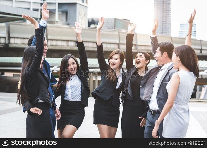 Portrait of successful group of business people at outdoor urban. Happy businessmen and businesswomen raising hand as team in satisfaction gesture. Successful group of people smiling after achievement