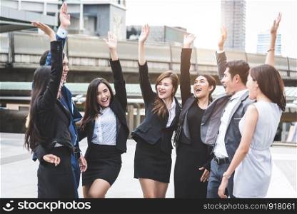 Portrait of successful group of business people at outdoor urban. Happy businessmen and businesswomen raising hand as team in satisfaction gesture. Successful group of people smiling after achievement