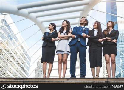 Portrait of successful group of business people looking up to sky as future. Happy businessmen and businesswomen team in satisfaction gesture. Successful group of people smiling in city background