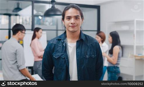 Portrait of successful handsome executive businessman smart casual wear looking at camera and smiling, happy in modern office workplace. Young Asia guy standing relax in contemporary meeting room.