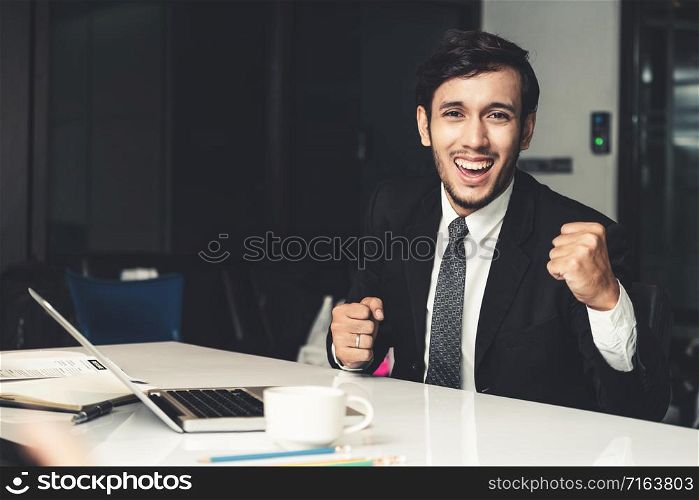 Portrait of successful happy young businessman smiling and looking at camera. Business success and victory celebration concept.