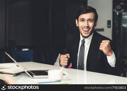 Portrait of successful happy young businessman smiling and looking at camera. Business success and victory celebration concept.