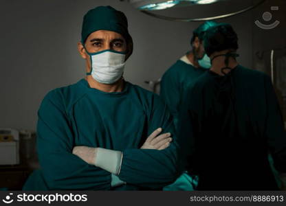 Portrait of surgical team leader in sterile operating room with his team and patient undergoing surgery. Confident and professional surgeon in full protective wear provide medical care to his patient.. Portrait of confident surgical team leader in sterile operating room.