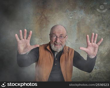 portrait of surprised and scared senior, bearded man trying to protect himself with hands, grunge urban background with some fog