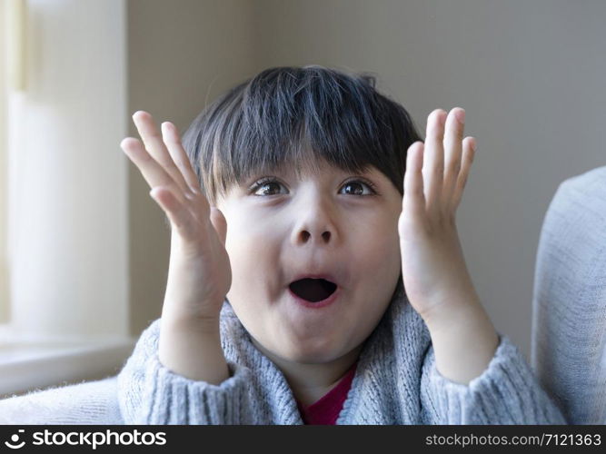 Portrait of surprised and shocked caucasian kid with eyes widened and mouth opened, Head shot funny kid, Child shouting loud with shocked face and raising hands up