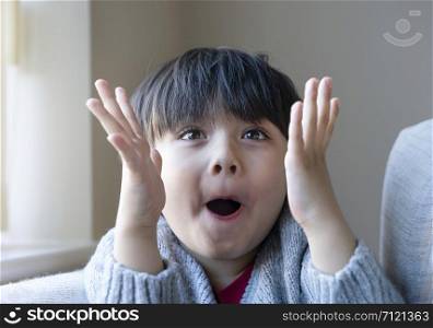 Portrait of surprised and shocked caucasian kid with eyes widened and mouth opened, Head shot funny kid, Child shouting loud with shocked face and raising hands up