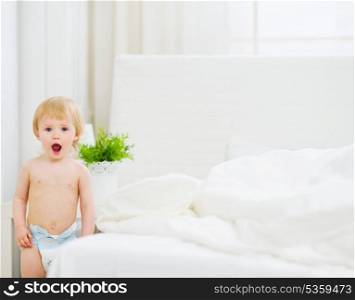 Portrait of surprised baby in bedroom
