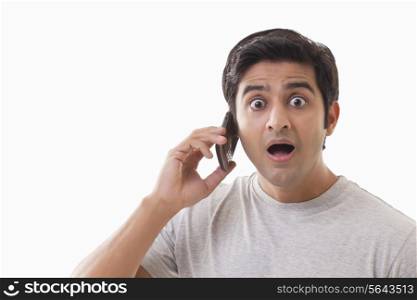 Portrait of surprised man using cell phone over white background