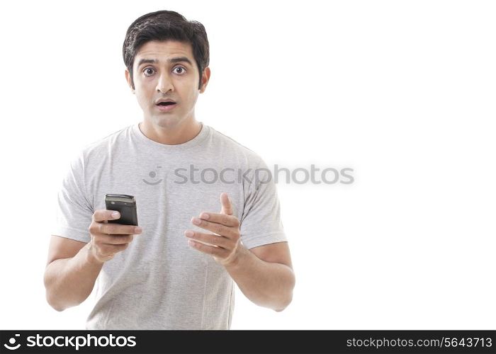 Portrait of surprised young man holding cell phone