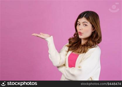 Portrait of Surprised young woman presenting or showing open hand palm with copy space for product over isolated pink background. Advertisement concept.