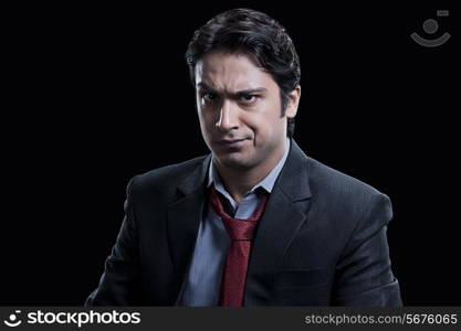 Portrait of suspicious businessman against black background