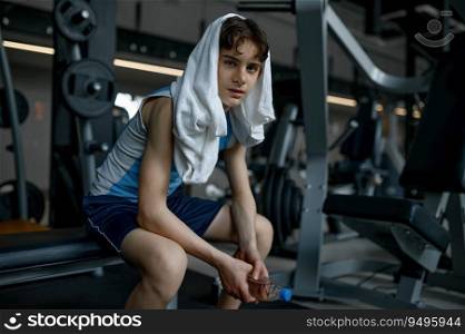 Portrait of sweaty teenager boy with towel on head rest after training at gym. Sport, hobby and healthy lifestyle for children. Portrait of sweaty teenager boy with towel on head rest after training at gym