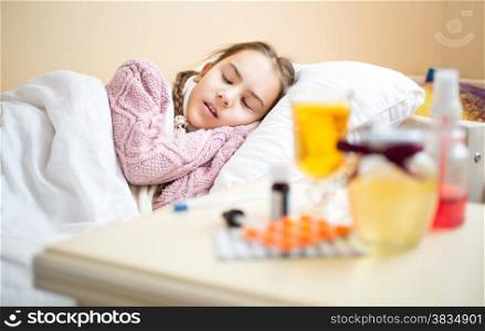 Portrait of table with medicines standing next to sick girls bed