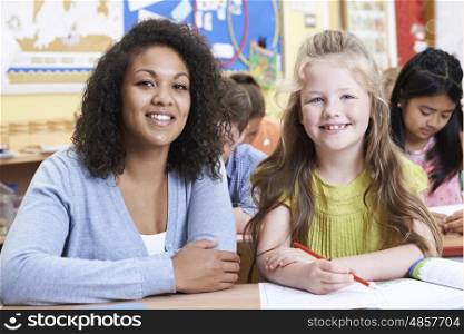 Portrait Of Teacher With Female Elementary School Pupil In Class