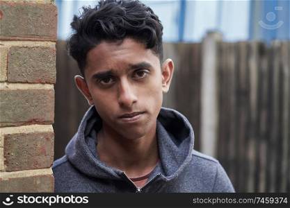 Portrait Of Teenage Boy Leaning Against Wall In Urban Setting                                
