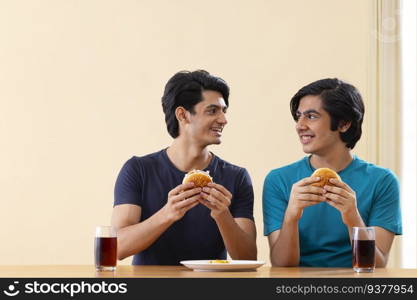 Portrait of teenage boys eating burgers together 