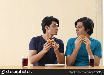 Portrait of teenage boys eating burgers together 