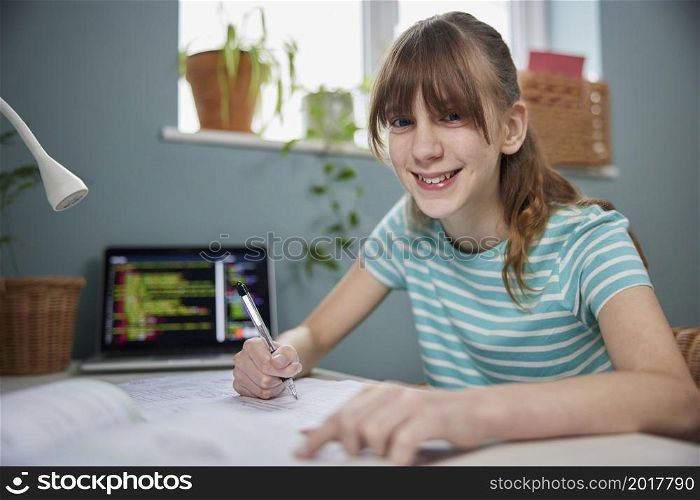 Portrait Of Teenage Girl Doing Homework At Desk In Bedroom