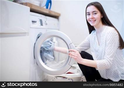 Portrait Of Teenage Girl Helping With Domestic Chores At Home Emptying Washing Machine