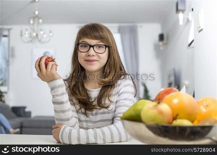 Portrait of teenage girl holding apple at home