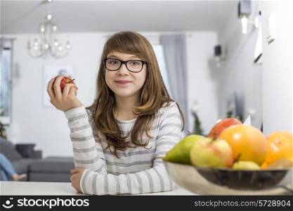 Portrait of teenage girl holding apple at home