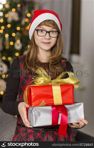 Portrait of teenage girl holding stack of Christmas presents
