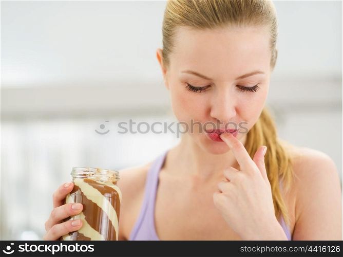 Portrait of teenage girl licking chocolate cream from finger