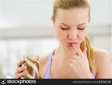 Portrait of teenage girl licking chocolate cream from finger