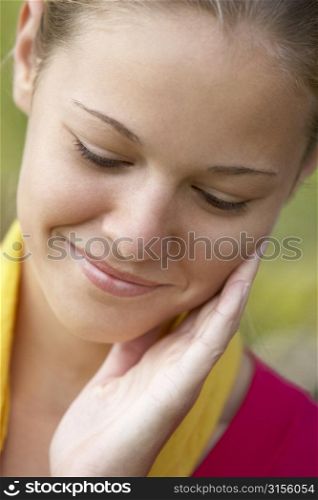 Portrait Of Teenage Girl Resting Head In Hands And Smiling
