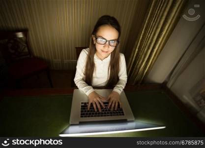 Portrait of teenage girl sitting in dark room with laptop