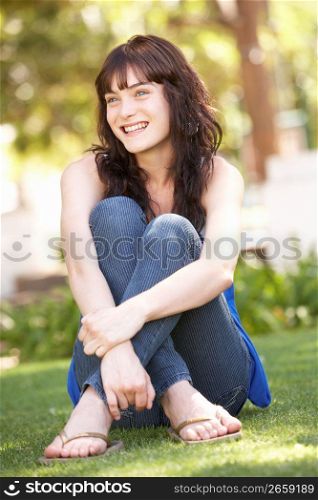 Portrait Of Teenage Girl Sitting In Park