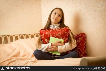 Portrait of teenage girl sitting on bed with her private diary